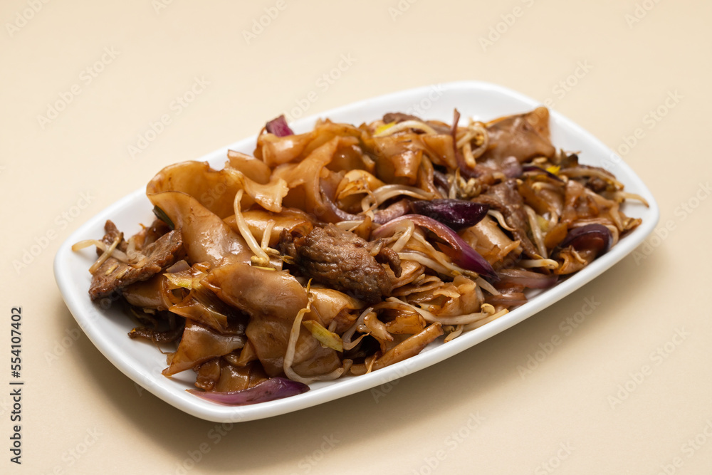 Fried noodles with vegetables and beef in white dish Fried noodles with vegetables and beef in white dish