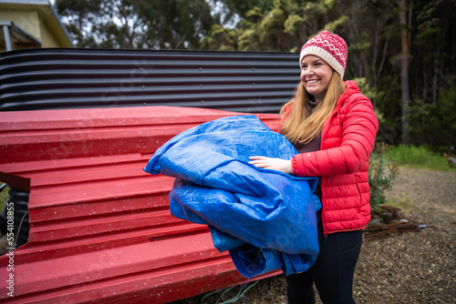 girl folding up a tent and blue tarp