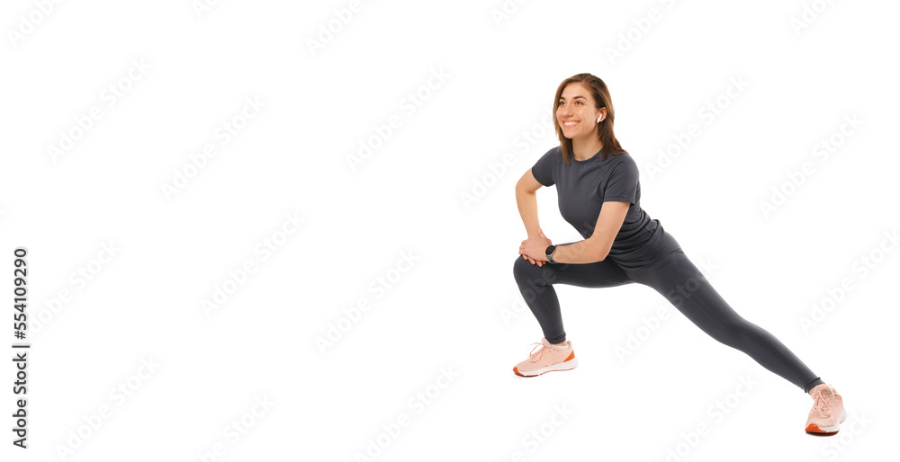 Young cheerful healthy woman si making some side lunges on right leg over white background.