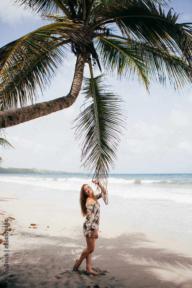 Beautiful girl near the palm tree on the tropical beach Beautiful girl near the palm tree on the tropical beach