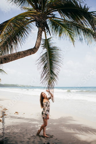 Beautiful girl near the palm tree on the tropical beach