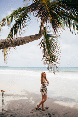Beautiful girl near the palm tree on the tropical beach © Олександр Пшевлоцьки