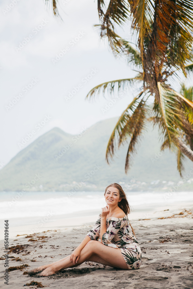 Beautiful girl near the palm tree on the tropical beach