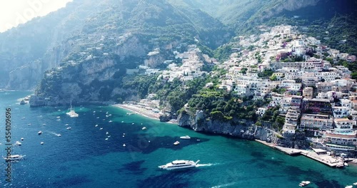 Aerial Drone View of Amalfi coast, Flying along the old town of Amalfi coast passing a waterway shore port, docks and boats in the sea. Postitano, Italy. Beautiful mountain destination. Cloudy day. photo