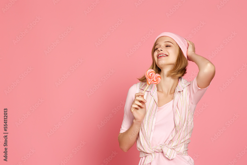 blonde woman holding candy on pink background. blonde woman holding candy on pink background.