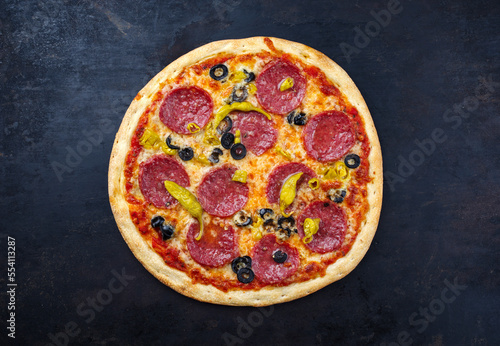 Traditionelle italienische Pizza al salame mit Salami, Mozzarella und Oliven serviert als Draufsicht auf einem alten rustikalen Board mit Textfreiraum 