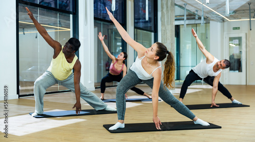 Group of young adults maintaining healthy lifestyle practicing pilates at yoga studio photo