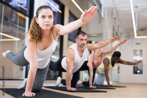 Portrait of young woman making pilates exercises with group in yoga studio