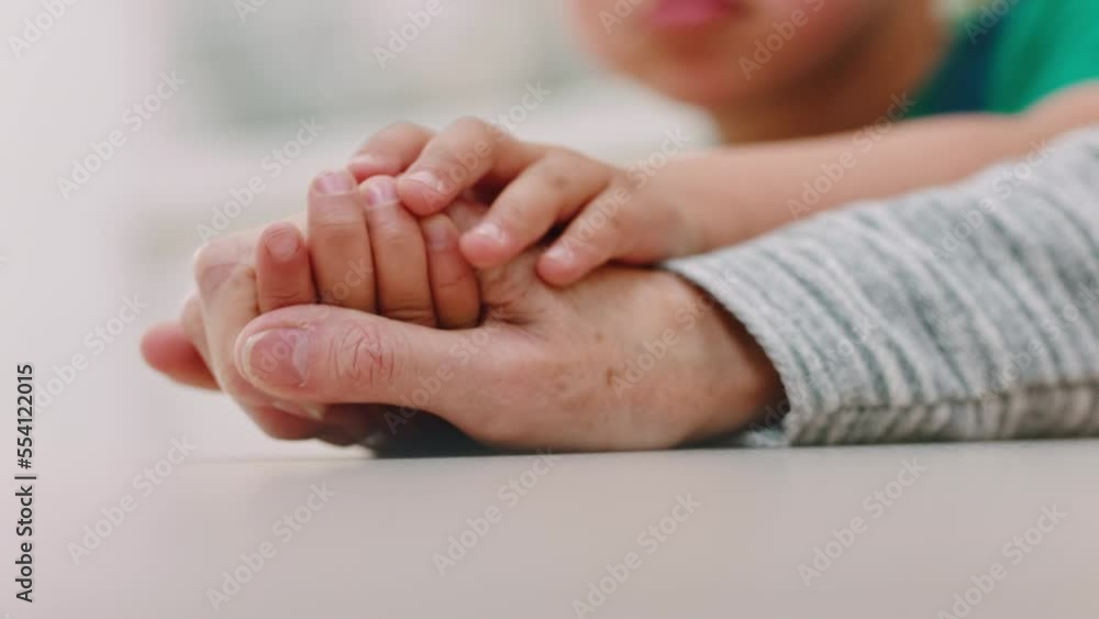 Child, mother and holding hands for support, love and family care with empathy, hope and trust together during sad time after loss or crisis. Hand of boy and woman on table at home for communication Child, mother and holding hands for support, love and family care with empathy, hope and trust together during sad time after loss or crisis. Hand of boy and woman on table at home for communication