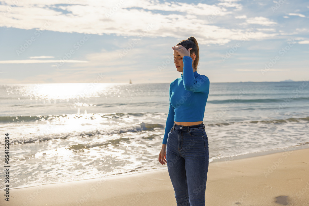 A young pretty girl in a blue jacket and jeans walks on the sea A young pretty girl in a blue jacket and jeans walks on the sea