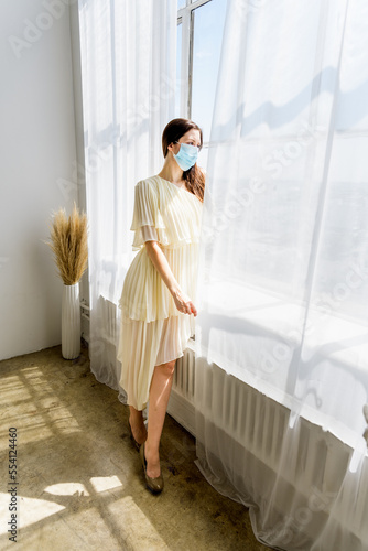Girl in face mask posing at window