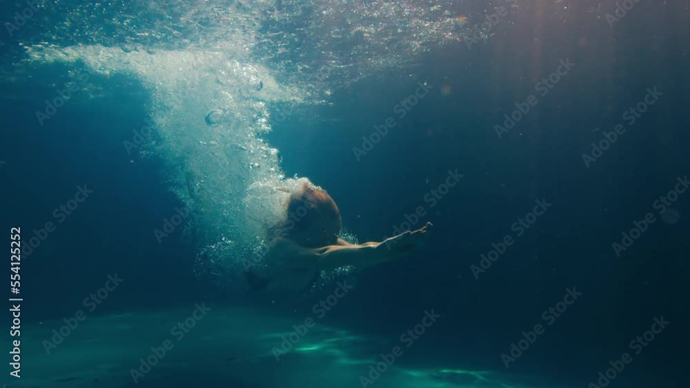 Woman dives in the pool. Underwater view of the girl diving in the pool
