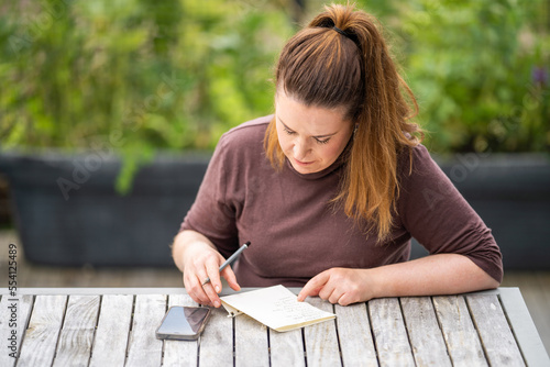 women teacher writing outside. wprking writing notes photo