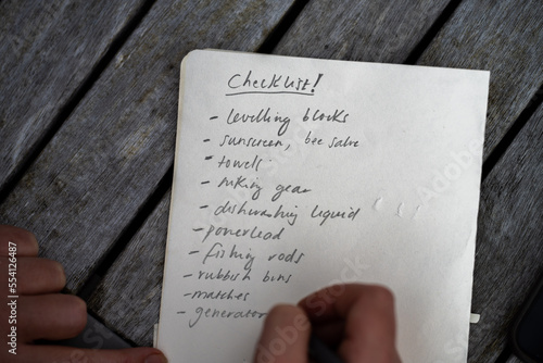 gril writing a camping list in a piece of paper. writing a check list with a pencil