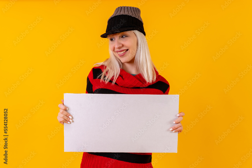 Holding blank empty ad poster, blonde caucasian girl on yellow background studio Holding blank empty ad poster, blonde caucasian girl on yellow background studio