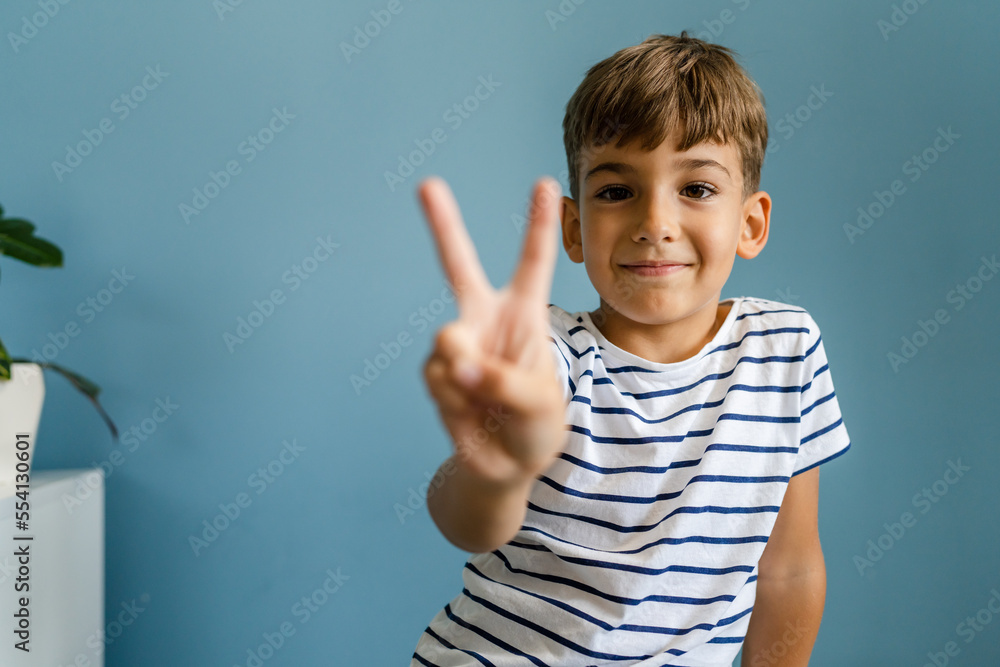 One caucasian boy child in front off blue wall portrait goofing around One caucasian boy child in front off blue wall portrait goofing around