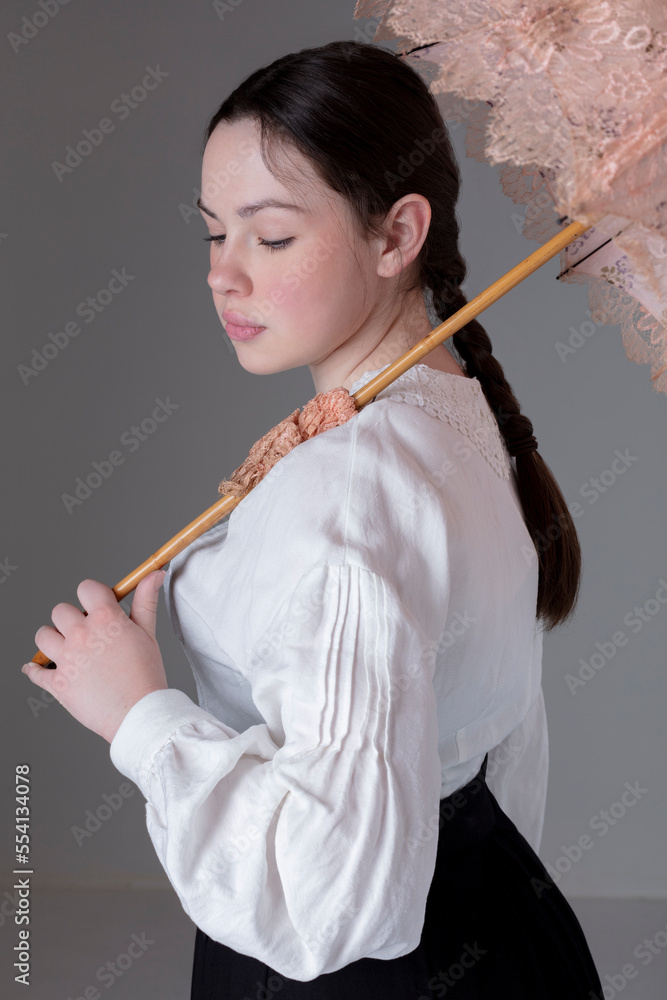 A young Victorian or Edwardian woman wearing a linen Garibaldi blouse and black skirt and holding a vintage parasol A young Victorian or Edwardian woman wearing a linen Garibaldi blouse and black skirt and holding a vintage parasol