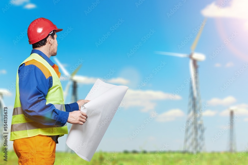 Young engineers working with wind turbine background