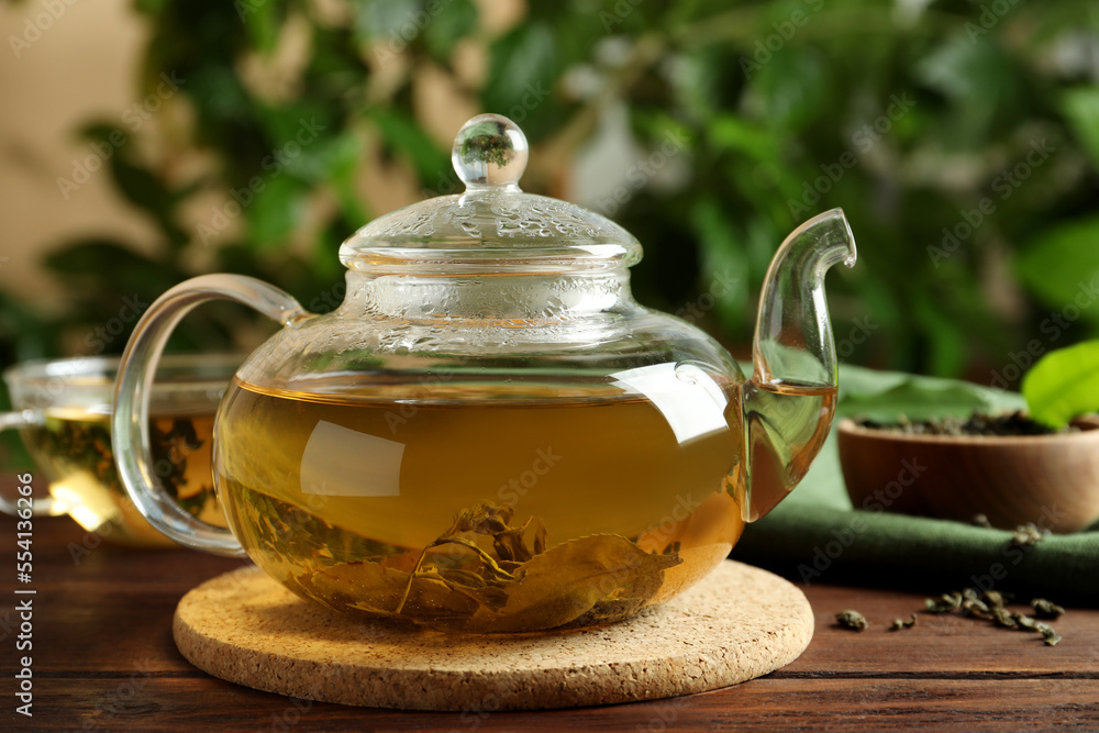 Glass teapot with fresh green tea on wooden table Glass teapot with fresh green tea on wooden table