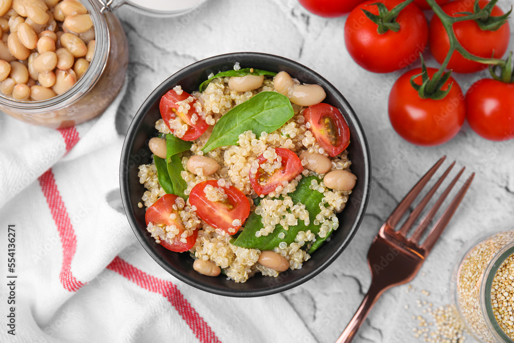 Delicious quinoa salad with tomatoes, beans and spinach leaves served on white textured table, flat lay Delicious quinoa salad with tomatoes, beans and spinach leaves served on white textured table, flat lay