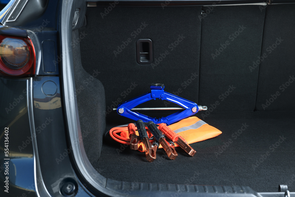 Naklejka premium Scissor jack, life vest and battery jumper cables in trunk. Car safety equipment