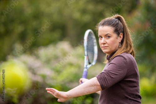 female tennis player practicing forehands and hitting tennis balls on a grass court in england photo