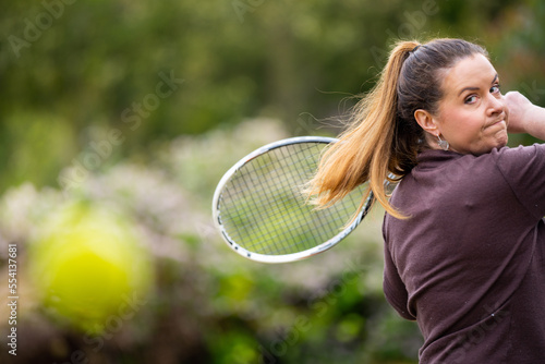 female tennis player practicing forehands and hitting tennis balls on a grass court in england © William