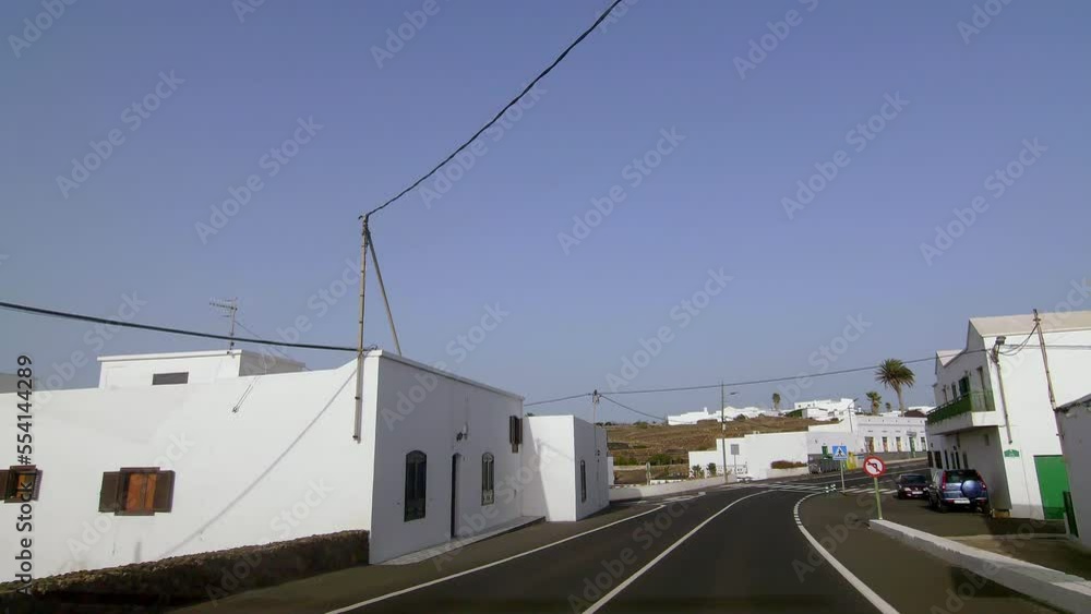 Calm driving on the roads of Lanzarote in the rural white villages from a car and we see the small white villages buildings by the side of the road on a cloudless sunny Calm driving on the roads of Lanzarote in the rural white villages from a car and we see the small white villages buildings by the side of the road on a cloudless sunny