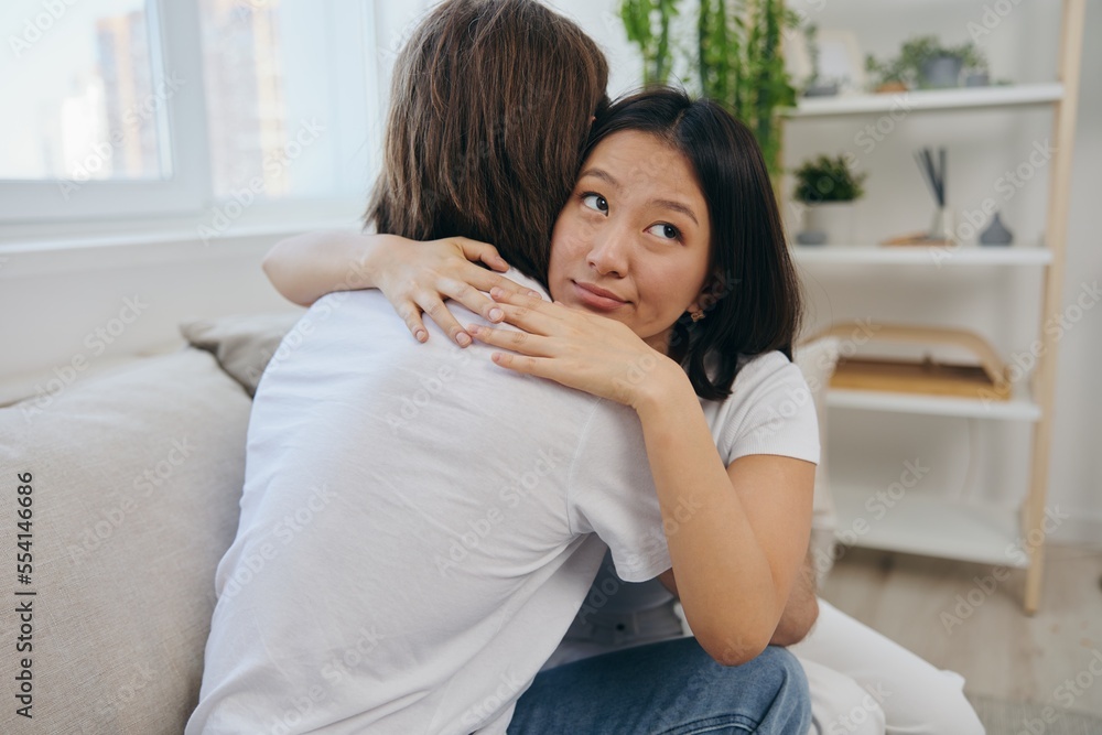 A man hugs his Asian woman friend at home. Psychological support for a friend A man hugs his Asian woman friend at home. Psychological support for a friend