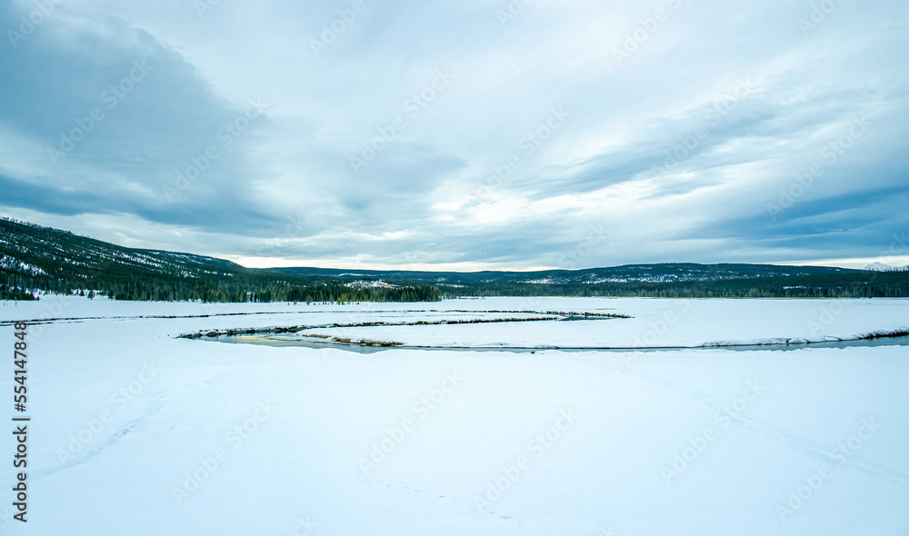 panoramic view of snow covered land with flowing winding river and trees