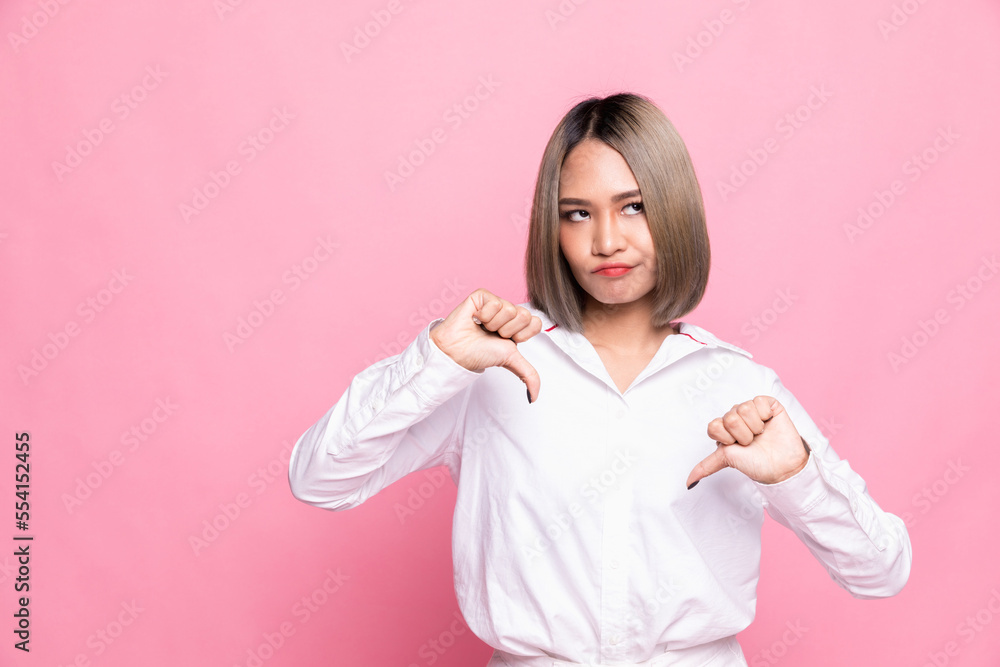 Young Asian woman isolated on pink background showing thumb down and expressing dislike. Young Asian woman isolated on pink background showing thumb down and expressing dislike.