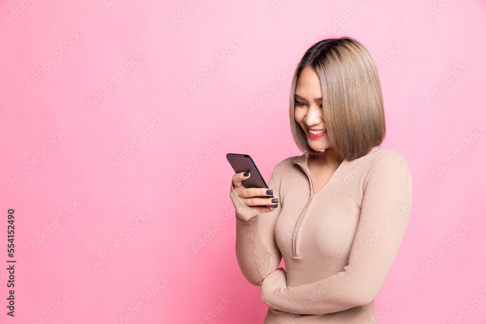 Smiling lovely young woman standing and using cell phone over pink background. Smiling lovely young woman standing and using cell phone over pink background.