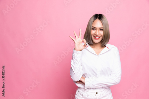 Happy Asian portrait beautiful cute young woman excited gesturing ok sign, studio shot isolated on pink background. © 2p2play