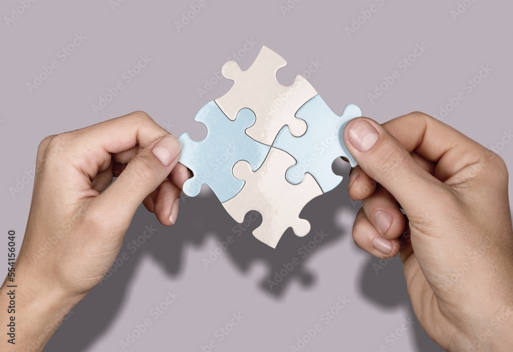 Business persons hands holding puzzle pieces Business persons hands holding puzzle pieces