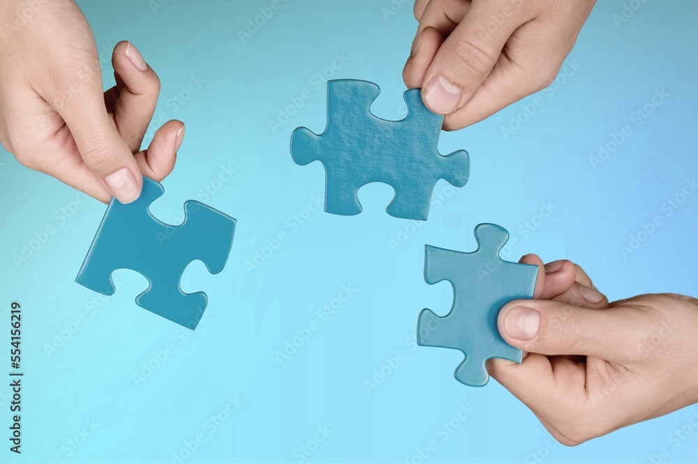 Business persons hands holding puzzle pieces Business persons hands holding puzzle pieces
