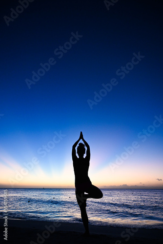 Tree pose - Woman doing a yoga pose in silhouette in front of a sunset - Caribbean ocean - wellness vibes - Negril Jamaica