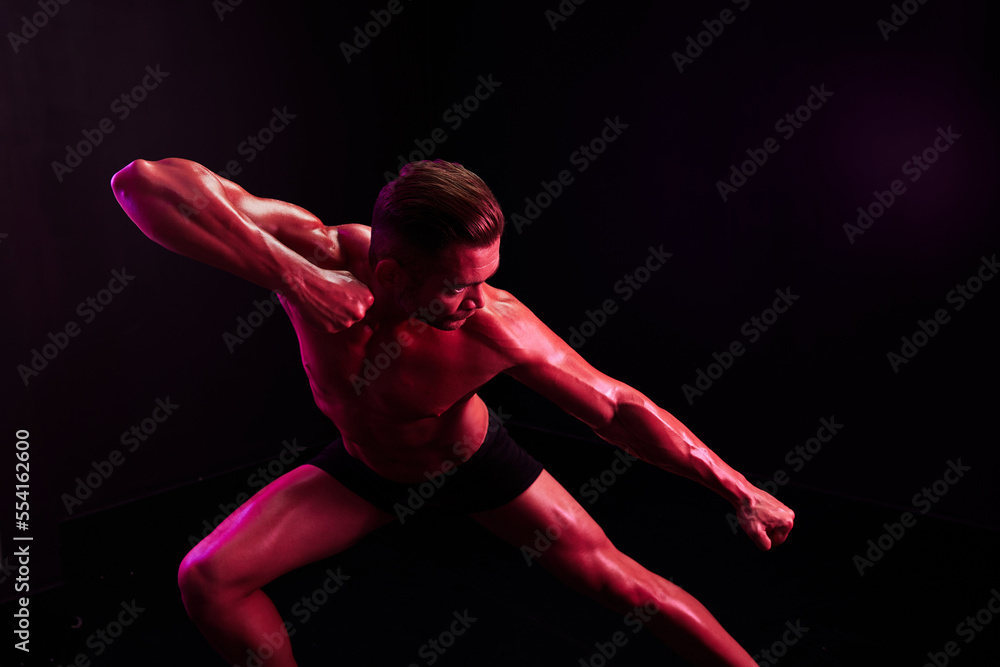 Man professional athletes with naked torso in athletic uniforms, isolated on a multicolored background in neon light. Advertising, sports, active lifestyle, competition, challenge concept