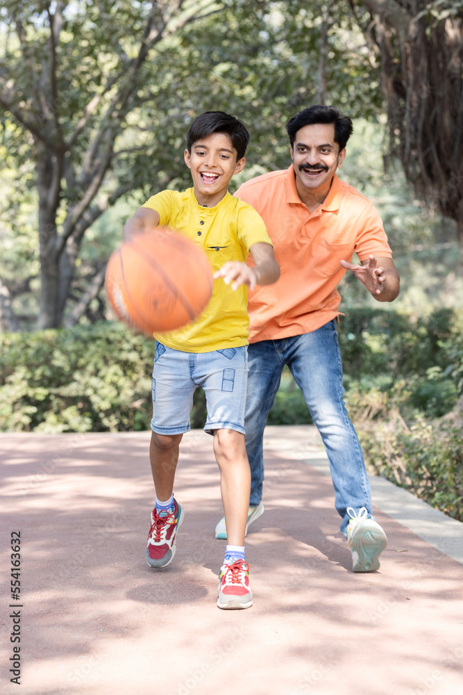 Father and son playing basketball at park.
