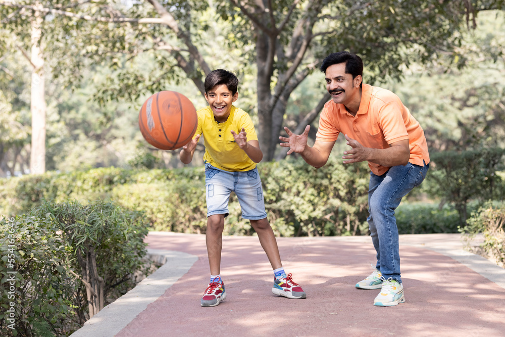 Father and son playing basketball at park. Father and son playing basketball at park.