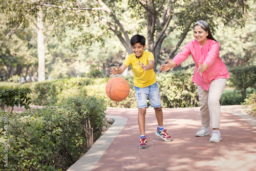 Grandmother and grandson having fun playing with basketball at park.