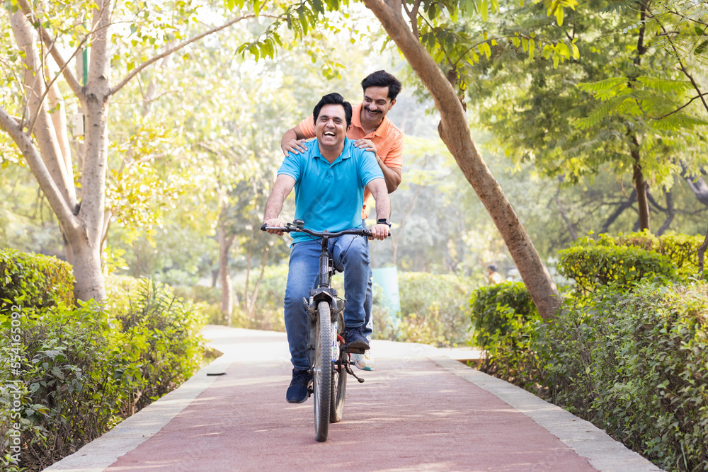 Obraz premium Two friends cyclist having fun riding bicycle outdoors on countryside road