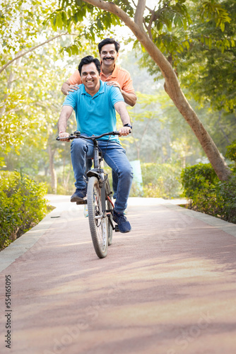 Two friends cyclist having fun riding bicycle outdoors on countryside road