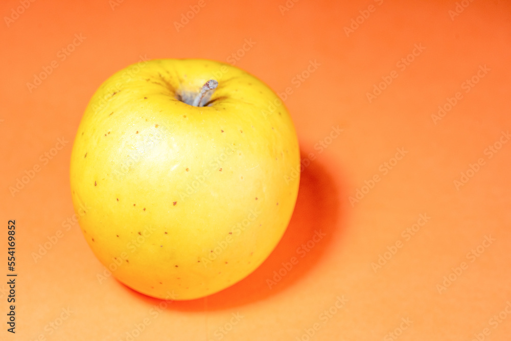 Fresh ripe juicy yellow apple fruit on orange background Fresh ripe juicy yellow apple fruit on orange background
