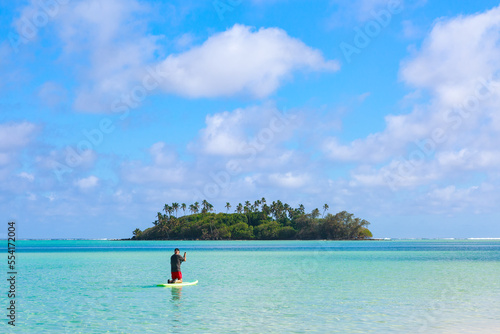 Man paddleboarding towards a tiny tropical island in the middle of a big lagoon. Photographed at Muri, Rarotonga, Cook Islands photo