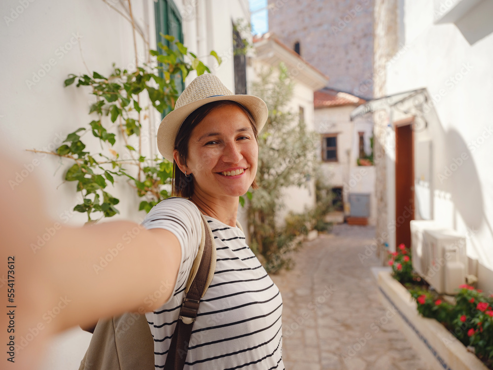 Marmaris is resort town on Turkish Riviera, known as Turquoise Coast. Marmaris is great place for sailing and diving. Tourist Woman on Beautiful Streets of old Marmaris taking selfie on smartphone.