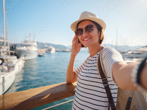 Marmaris is resort town on Turkish Riviera, also known as Turquoise Coast. Marmaris is great place for sailing and diving. Asian woman with hat walking on pier in harbor.