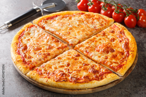 Homemade New York style pizza with mozzarella cheese and spicy tomato sauce close-up on a wooden board on the table. Horizontal