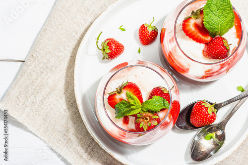 Italian dessert panna cotta in glass with strawberries. Healthy sweet food, hard light, dark shadow