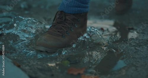 Boot stepping into a puddle with a big splash of water in slow motion 4K
