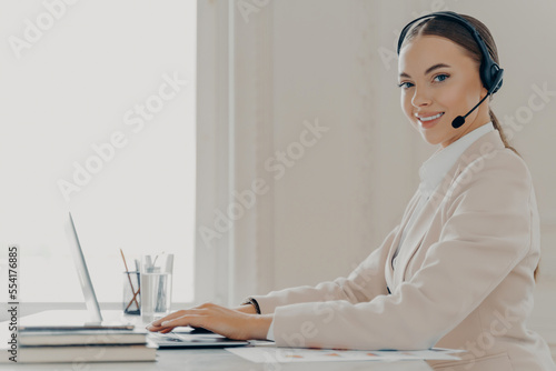 Smiling call center agent in headset consulting client